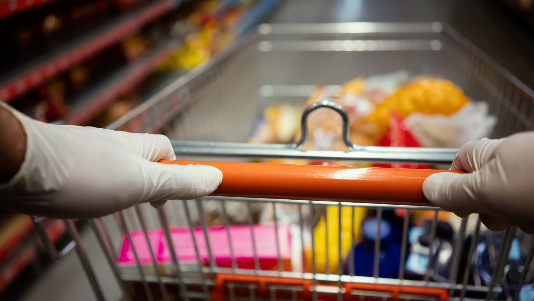 someone wearing gloves pushing grocery cart